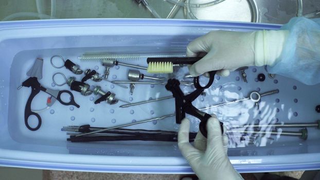 Close up of nurse's hands washing medical instrument after operation