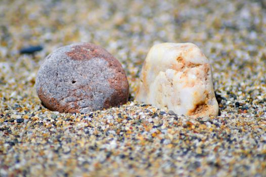 Two pebbles on a background of grains of sand on the beach of Amoudara
