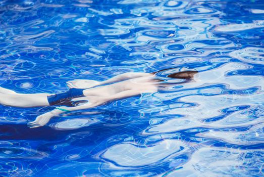 Young man swimming in the pool underwater.