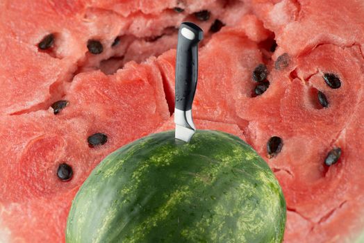 Riped watermelon with knife and red meat background.