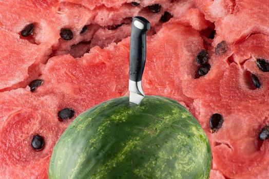 Riped watermelon with knife and red meat background.