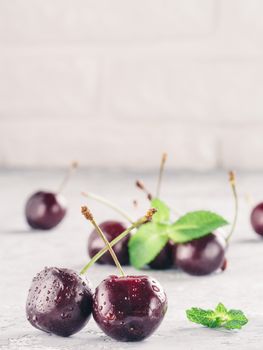 Close up view of fresh ripe cherry. Cherry and mint leaf on gray concrete background. Vertical. Copy space.