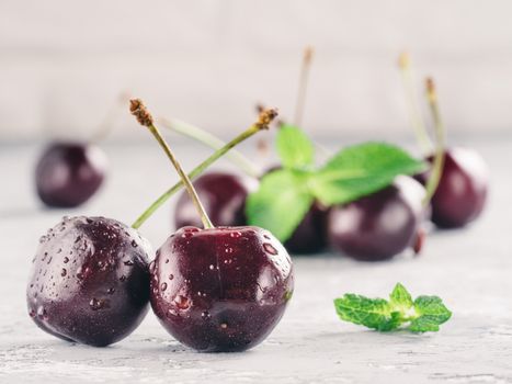 Close up view of fresh ripe cherry. Cherry and mint leaf on gray concrete background. Copy space.