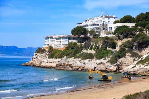 View of the empty beach with the bulldozer and the excavator. Salou, Spain