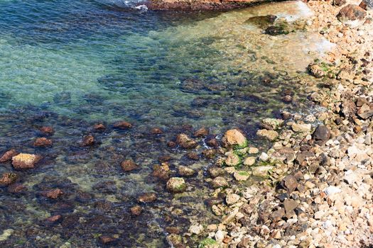 Colorful rocks with green moss in shallow sea water background