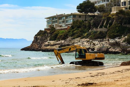 View of the empty beach with the working excavator. Salou, Spain