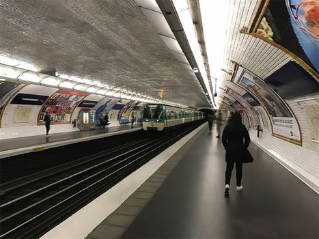 A woman walks along the platform waiting for a train ride on the metro.