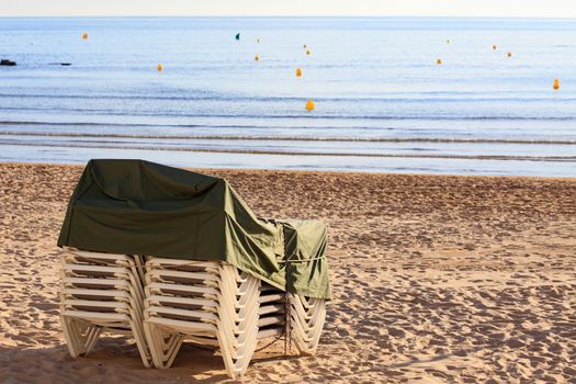 Pile of deck chairs on the empty sea beach