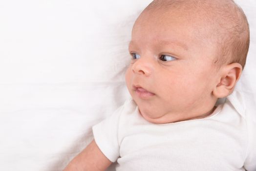 Mixed race south asian and caucasian newborn baby on white sheet