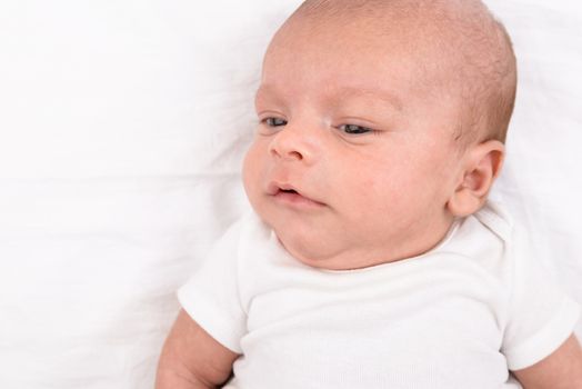 Mixed race south asian and caucasian newborn baby on white sheet