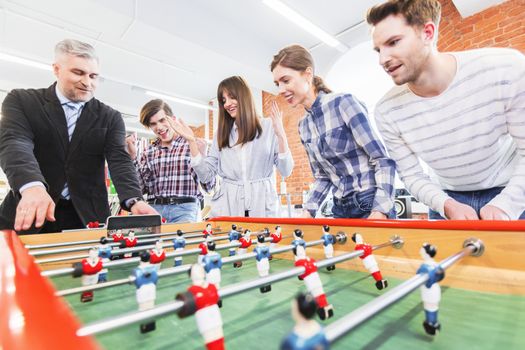 Group of happy people playing table soccer together