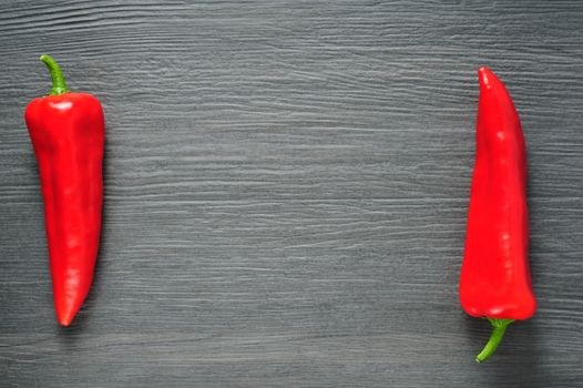 Two opposite ripe sweet red Kapia peppers on dark shale stone background