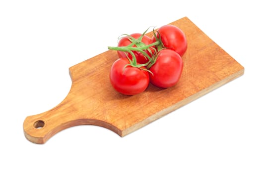 Cluster of the ripe red tomatoes on the wooden cutting board closeup on a light background
