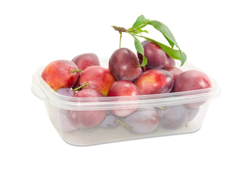Fresh Victoria plums with twig and leaves in the transparent plastic container on a light background

