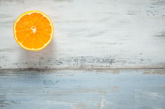One slice of fresh oranges on painted wooden board, looks like sun at sky over a sea, copy space