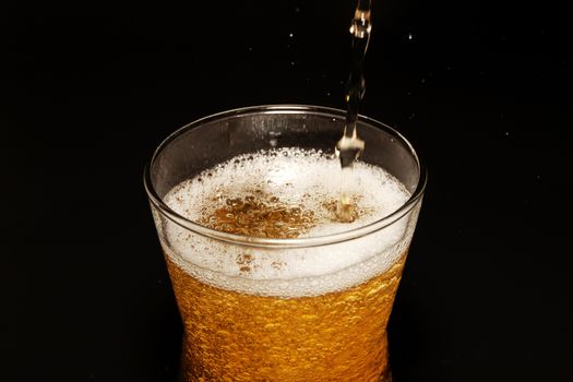 Beer in glass isolated on black background. Pour beer