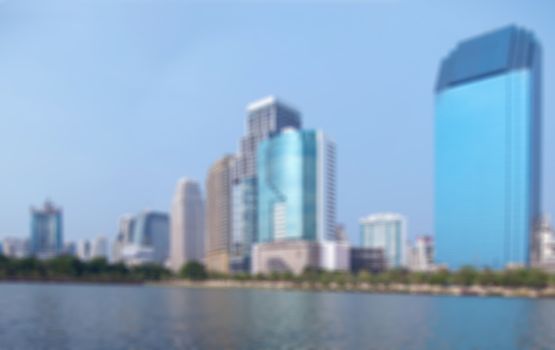 Abstract blurred cityscape with lake and high-rise building.