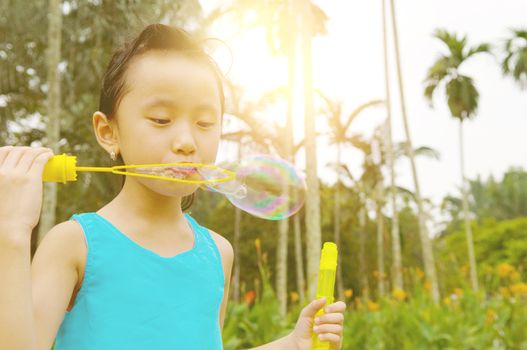 Asian girl blowing bubbles outdoor