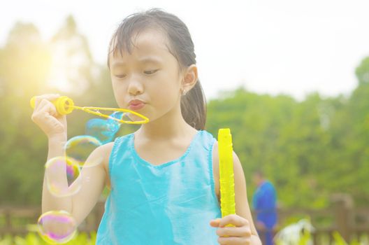 Asian girl blowing bubbles outdoor