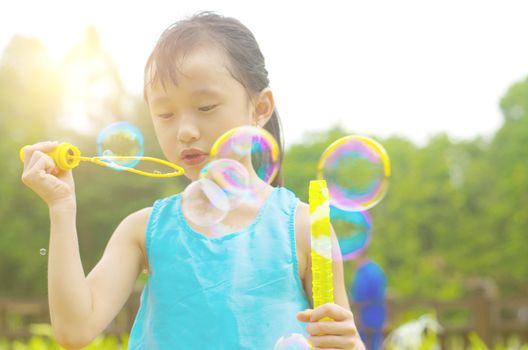 Asian girl blowing bubbles outdoor