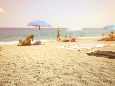 beach sand with blurry people relaxing by the sea in the background 