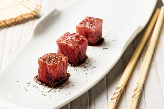 Tuna sashimi dipped in soy sauce, thick salt and dill with chopsticks and bamboo mat. Raw fish in traditional Japanese style. Horizontal image.