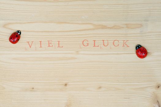 Stamped german text for Good luck on wood and ladybug, background