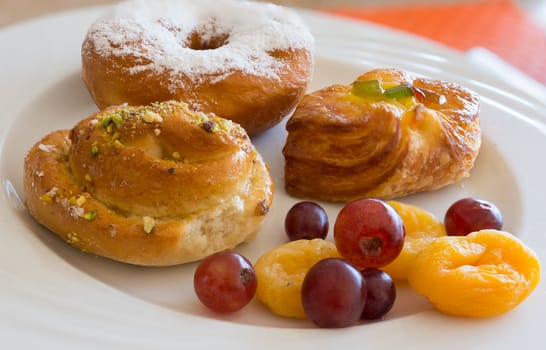 Danish pastry and  fruits on white dish,close-up.