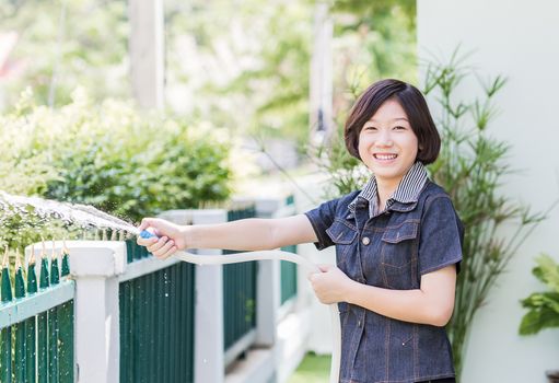 Asian women standing Spraying a tree in garden at her house