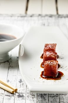 Tuna sashimi dipped in soy sauce,  thick salt and dill on old white wooden board with chopsticks and sauce bowl. Raw fish in traditional Japanese style. Vertical image.