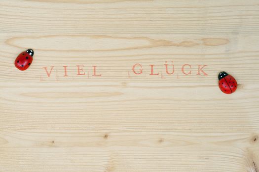 Stamped german text for Good luck on wood and ladybug, background