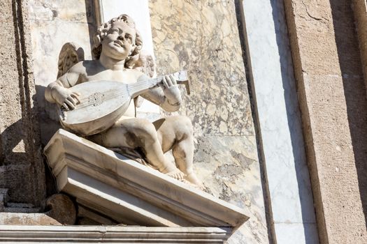 the statue of a cherub with a mandolin