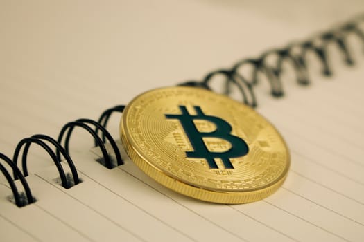 Cryptocurrency physical gold bitcoin coin in notebook.