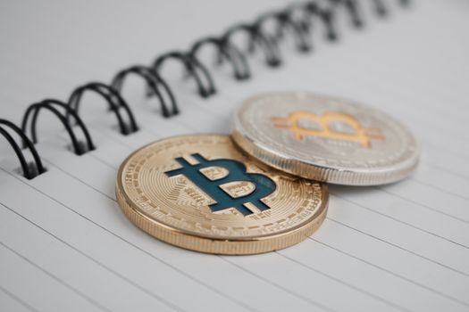 Cryptocurrency physical silver bitcoin and gold bitcoin in notebook.