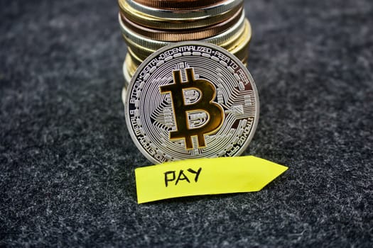 Cryptocurrency physical silver bitcoin coin near yellow arrow pay