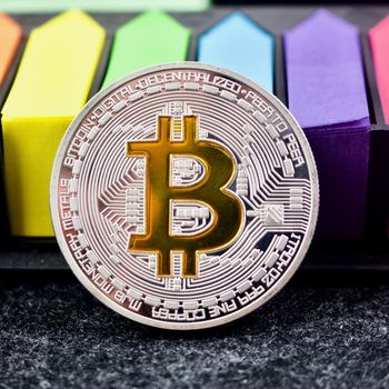 Cryptocurrency physical silver bitcoin coin on colorful pattern