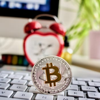Cryptocurrency physical silver bitcoin coin, keyboard, screen and clock.