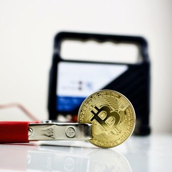 Black car charger connected with bitcoin gold cryptocurrency coin.