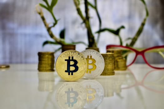 Digital currency physical gold and silver bitcoin coins near pink glasses