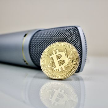 Gold bitcoin cryptocurrency coin and silver microphone.