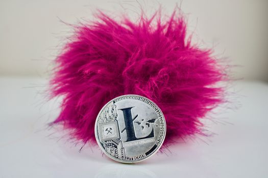 Silver litecoin coin with a pink hairy ball. Digital cryptocurrency.