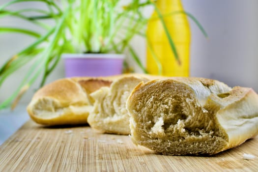 Fresh rolls, green flower, wooden kitchen board.