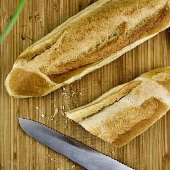 Wooden board with knife and fresh rolls