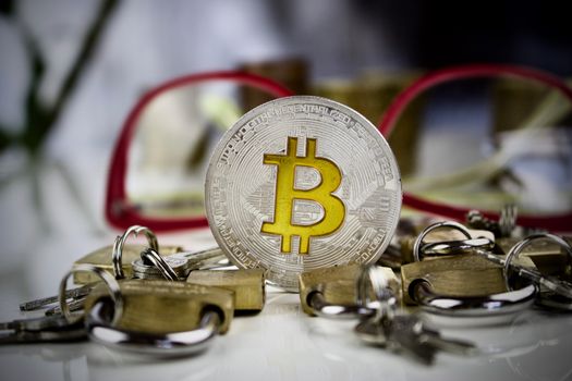 Cryptocurrency physical silver bitcoin coin with a yellow sign near padlocks
