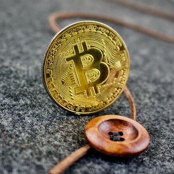 Cryptocurrency gold physical bitcoin coin and wooden button.