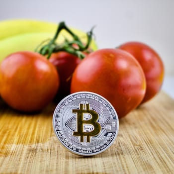 Cryptocurrency silver bitcoin coin, tomatoes and bananas
