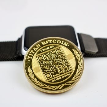Cryptocurrency physical gold titan bitcoin and black smartwatch.