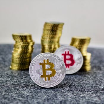 Cryptocurrency physical silver bitcoin coin with yellow and pink sign.