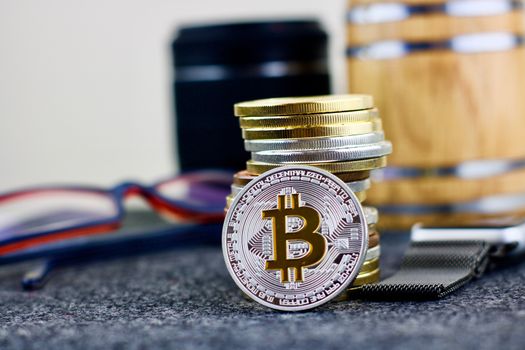 Cryptocurrency physical silver bitcoin coin near glasses, money and camera lenses