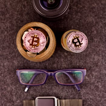 Cryptocurrency physical silver bitcoin coin in a barrel. Glasses, lens, watch.